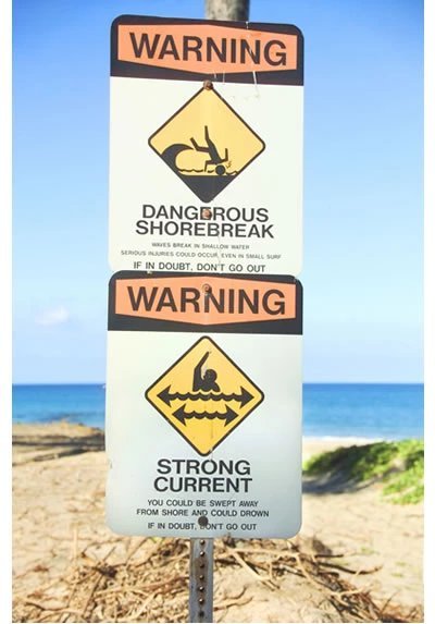 Hawaii beach warning sign advising visitors about ocean safety hazards